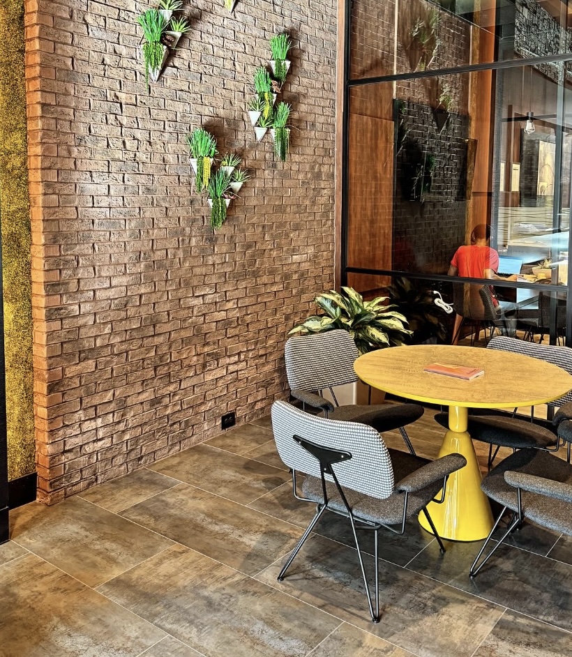 Before: Empty social lounge wall with plants and seating
